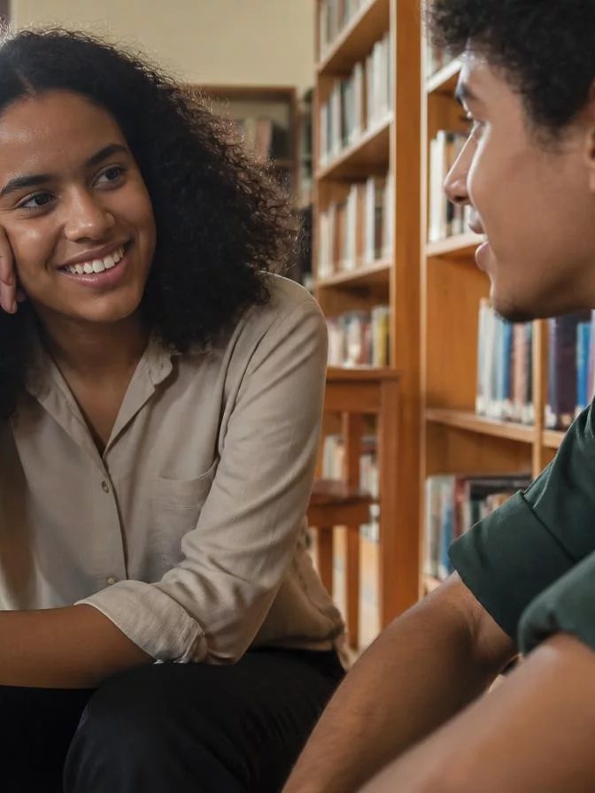 Duas participantes conversando de pé no corredor entre prateleiras de livros